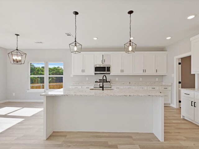 1400 Belzise Ter, Fort Worth, TX 76104 - kitchen featuring stainless steel microwave, a kitchen island with sink, light wood-style flooring, and recessed lighting