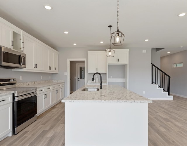 1400 Belzise Ter, Fort Worth, TX 76104 - kitchen featuring appliances with stainless steel finishes, light wood-style floors, light stone counters, an island with sink, and white cabinetry