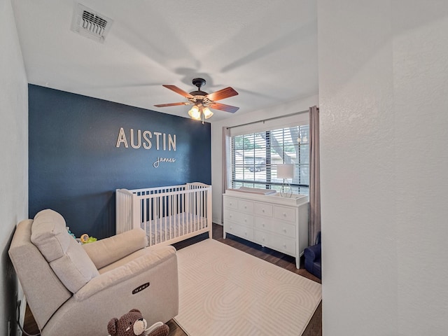 3717 Fairhaven Dr, Fort Worth, TX 76123 - bedroom featuring wood finished floors, a nursery area, a textured wall, and a ceiling fan