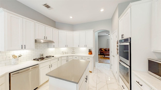 3009 Wood Trl, Flower Mound, TX 75022 - kitchen with stainless steel appliances, light marble finish floors, arched walkways, under cabinet range hood, and recessed lighting