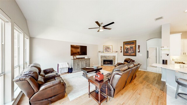 3009 Wood Trl, Flower Mound, TX 75022 - living room with a tile fireplace, a ceiling fan, vaulted ceiling, light wood-style floors, and arched walkways