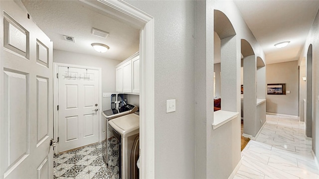 3009 Wood Trl, Flower Mound, TX 75022 - washroom featuring cabinet space, arched walkways, washing machine and clothes dryer, and light marble finish floors