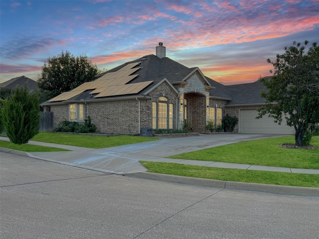 14001 Zippo Way, Fort Worth, TX 76052 - view of front facade featuring concrete driveway, roof mounted solar panels, a chimney, brick siding, and a garage