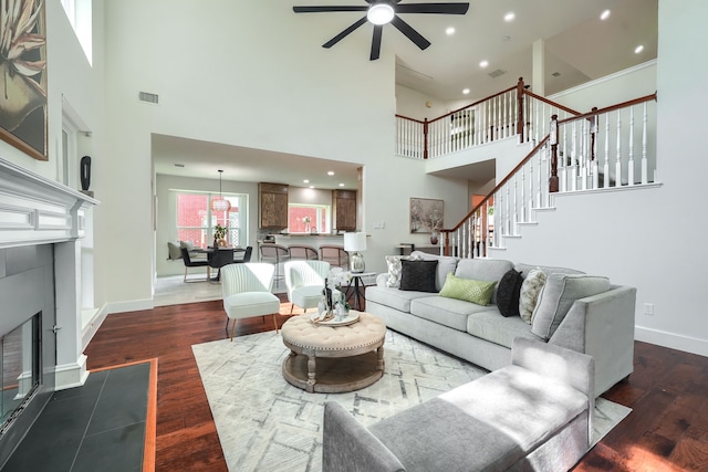 3609 Whitehaven Dr, Plano, TX 75093 - living room with ceiling fan, a fireplace with flush hearth, a towering ceiling, dark wood-style floors, and stairs