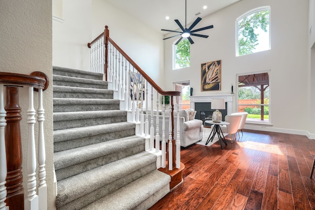 3609 Whitehaven Dr, Plano, TX 75093 - stairway with a towering ceiling, ceiling fan, wood-type flooring, a glass covered fireplace, and recessed lighting