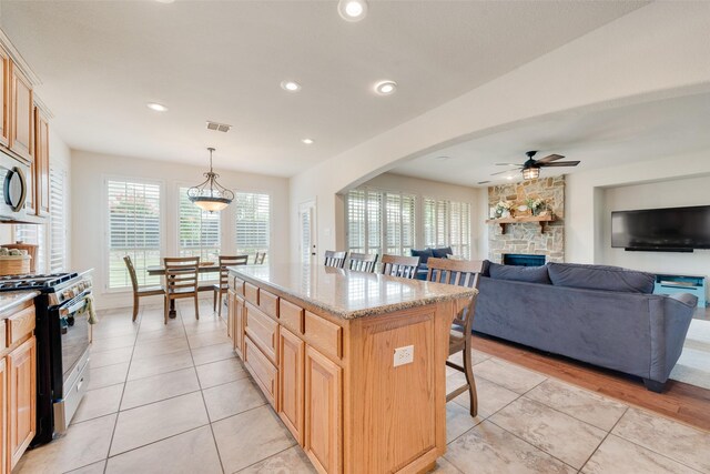 1021 Springtown St, Forney, TX 75126 - kitchen with stainless steel appliances, a breakfast bar, ceiling fan, light tile patterned flooring, and a fireplace