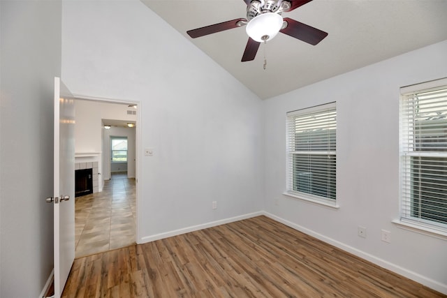 308 Crowe Dr, Euless, TX 76040 - empty room featuring lofted ceiling, a tile fireplace, ceiling fan, and light wood finished floors