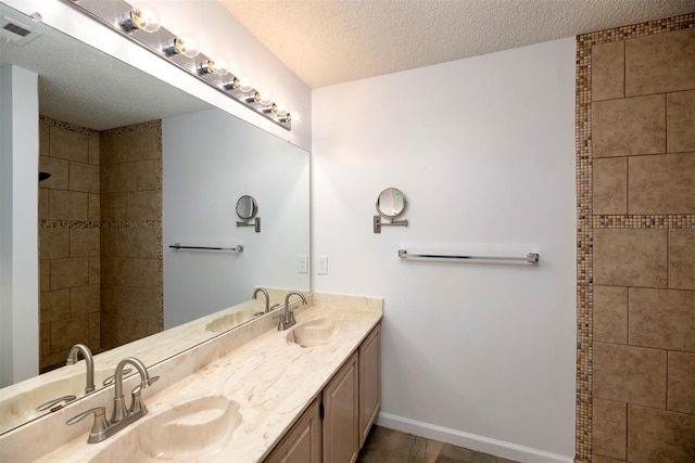 308 Crowe Dr, Euless, TX 76040 - bathroom with double vanity, a textured ceiling, and a tile shower