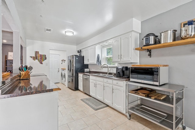 3905 Chestnut St, Fort Worth, TX 76137 - kitchen featuring washer and clothes dryer, appliances with stainless steel finishes, dark countertops, white cabinets, and light tile patterned flooring