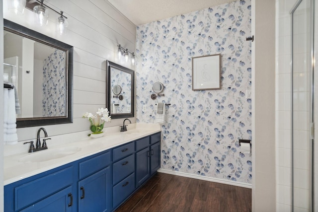 9129 Apollo Ct, Frisco, TX 75033 - bathroom with wallpapered walls, wood finished floors, double vanity, and an enclosed shower