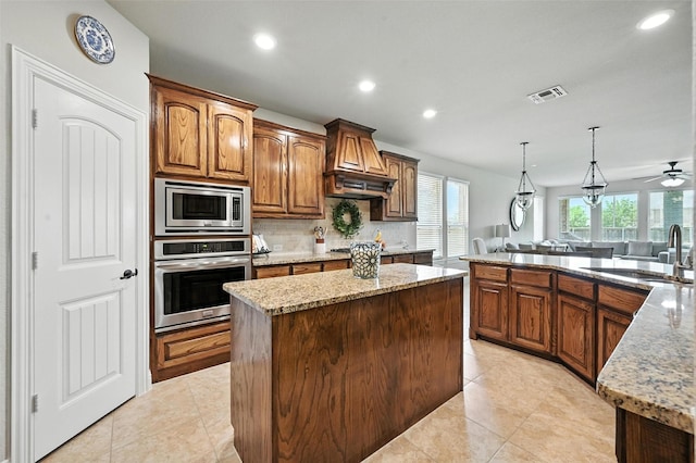 10704 Parnell Dr, Mckinney, TX 75072 - kitchen with stainless steel appliances, custom exhaust hood, a kitchen island, light stone counters, and recessed lighting