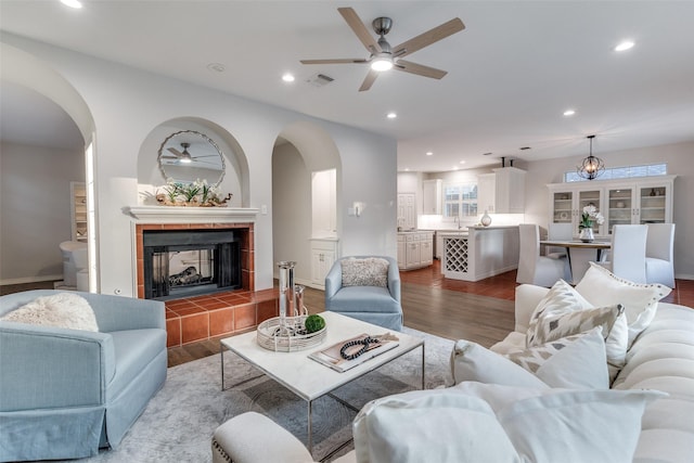 8931 Club Creek Cir, Dallas, TX 75238 - living room with arched walkways, a ceiling fan, wood finished floors, a tile fireplace, and recessed lighting