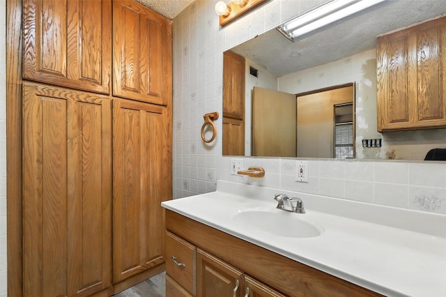221 E 7th St, Weatherford, TX 76086 - bathroom with a textured ceiling, vanity, tile walls, and backsplash