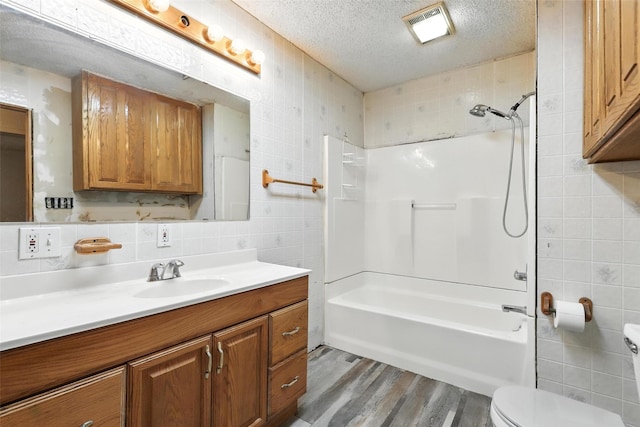 221 E 7th St, Weatherford, TX 76086 - full bathroom with tile walls, vanity, wood finished floors, a textured ceiling, and shower / bathtub combination