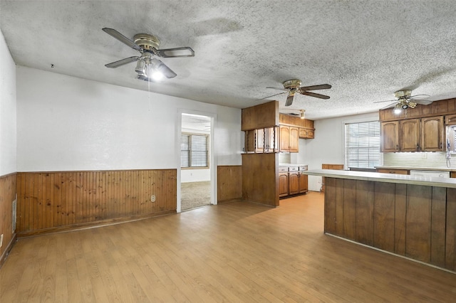 221 E 7th St, Weatherford, TX 76086 - kitchen featuring ceiling fan, light countertops, wainscoting, light wood-style flooring, and brown cabinets
