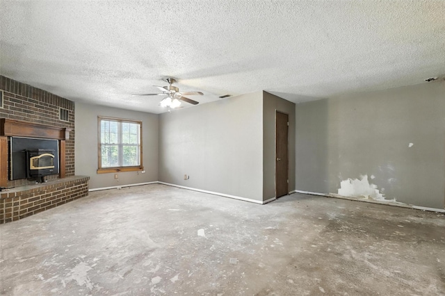 221 E 7th St, Weatherford, TX 76086 - unfurnished living room with concrete floors, a ceiling fan, a wood stove, and a textured ceiling