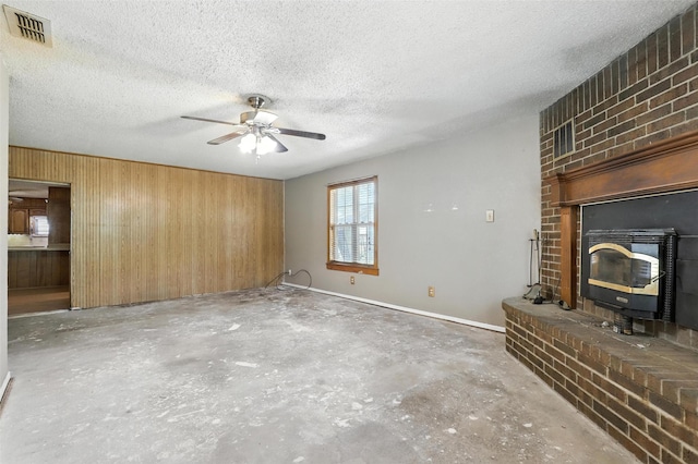 221 E 7th St, Weatherford, TX 76086 - unfurnished living room with unfinished concrete flooring, a ceiling fan, wooden walls, a textured ceiling, and a wood stove
