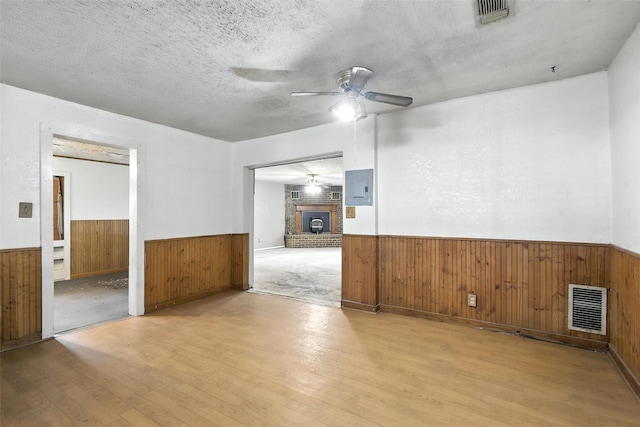 221 E 7th St, Weatherford, TX 76086 - spare room featuring wainscoting, wooden walls, ceiling fan, wood finished floors, and electric panel