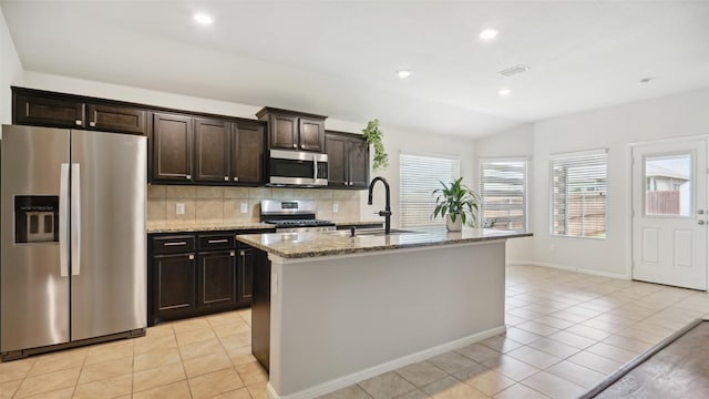 6348 Porthole Ln, Fort Worth, TX 76179 - kitchen with stainless steel appliances, light tile patterned floors, light stone counters, decorative backsplash, and a center island with sink