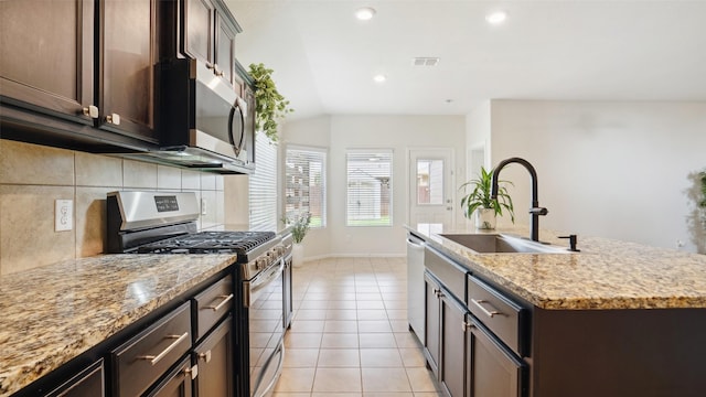 6348 Porthole Ln, Fort Worth, TX 76179 - kitchen featuring stainless steel appliances, a center island with sink, vaulted ceiling, dark brown cabinets, and light tile patterned floors