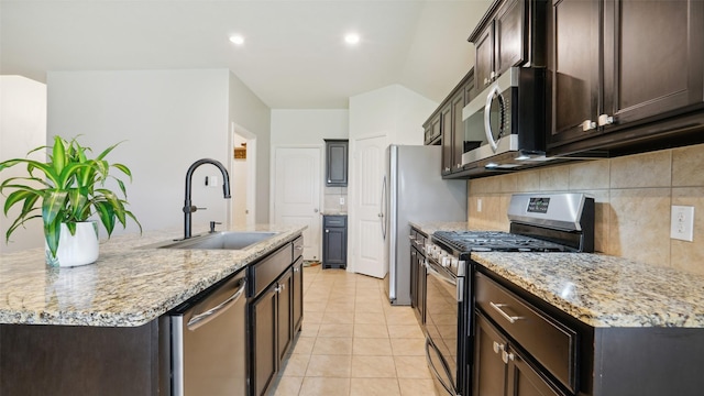 6348 Porthole Ln, Fort Worth, TX 76179 - kitchen featuring stainless steel appliances, a center island with sink, backsplash, dark brown cabinetry, and light tile patterned floors