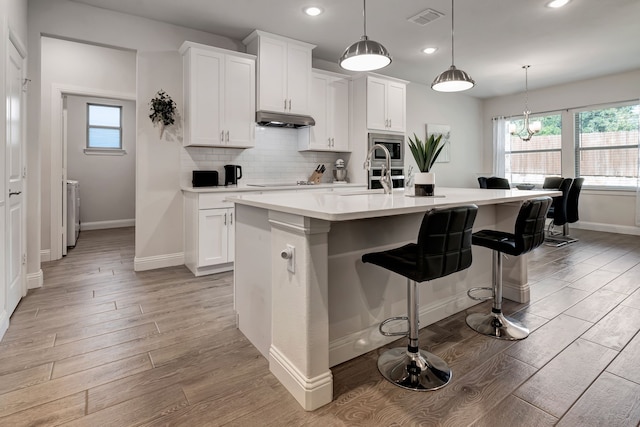 237 Gardenia Dr, Azle, TX 76020 - kitchen featuring recessed lighting, light wood-style floors, under cabinet range hood, light countertops, and white cabinets