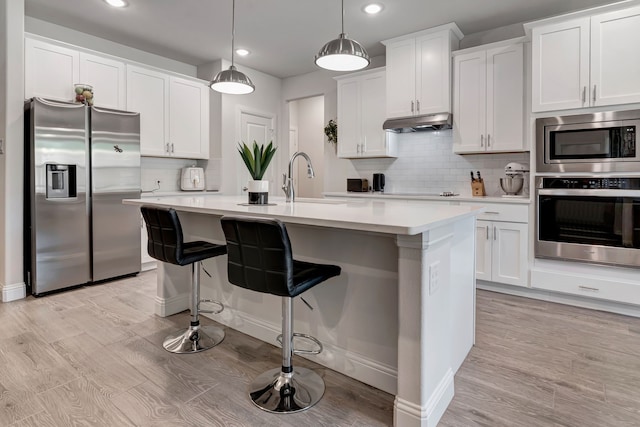237 Gardenia Dr, Azle, TX 76020 - kitchen featuring appliances with stainless steel finishes, recessed lighting, light countertops, under cabinet range hood, and an island with sink