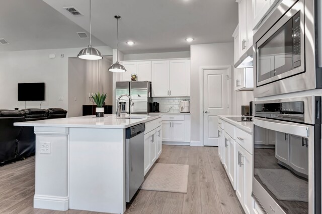 237 Gardenia Dr, Azle, TX 76020 - kitchen with appliances with stainless steel finishes, light wood finished floors, tasteful backsplash, open floor plan, and decorative light fixtures