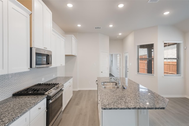 3928 Aqua Ln, Sherman, TX 75090 - kitchen featuring stainless steel appliances, light wood finished floors, a center island with sink, white cabinetry, and decorative backsplash
