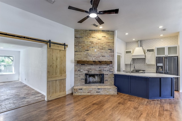 700 Stanford Dr, Waxahachie, TX 75165 - kitchen featuring custom exhaust hood, ceiling fan, wood finished floors, tasteful backsplash, and glass insert cabinets