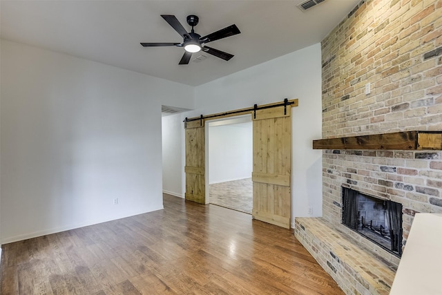 700 Stanford Dr, Waxahachie, TX 75165 - unfurnished living room with wood finished floors, ceiling fan, a barn door, and a fireplace