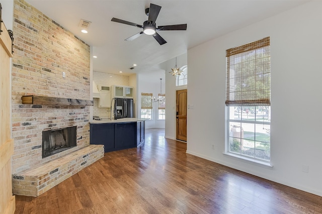 700 Stanford Dr, Waxahachie, TX 75165 - unfurnished living room with a chandelier, a fireplace, wood finished floors, a ceiling fan, and recessed lighting