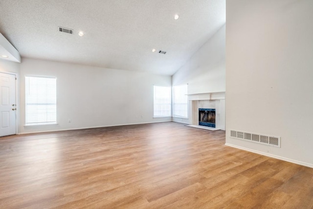 8801 Holly St, Frisco, TX 75034 - unfurnished living room featuring light wood-type flooring, a tile fireplace, recessed lighting, and high vaulted ceiling