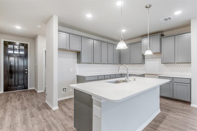 1327 Burgess St, Royse City, TX 75189 - kitchen with gray cabinetry, a center island with sink, light wood-type flooring, hanging light fixtures, and recessed lighting