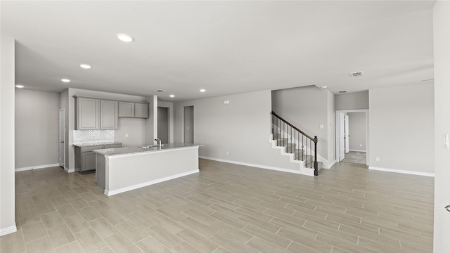 1327 Burgess St, Royse City, TX 75189 - kitchen featuring gray cabinets, recessed lighting, a center island with sink, decorative backsplash, and open floor plan