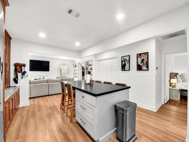3921 Bryce Ave, Fort Worth, TX 76107 - kitchen with light wood-style flooring, recessed lighting, a breakfast bar area, dark countertops, and a kitchen island
