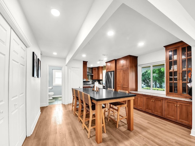 3921 Bryce Ave, Fort Worth, TX 76107 - kitchen featuring stainless steel appliances, recessed lighting, light wood-type flooring, glass insert cabinets, and brown cabinetry