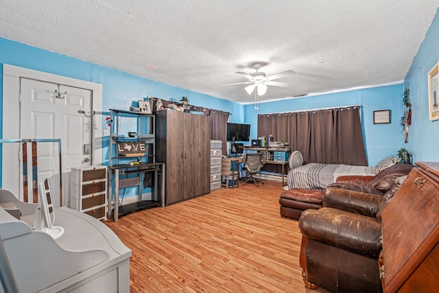 814 N Ollie St, Stephenville, TX 76401 - bedroom with light wood-type flooring, a desk, a textured ceiling, and a ceiling fan