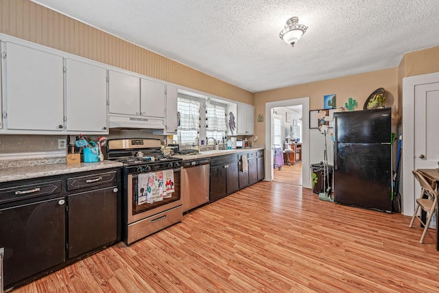 814 N Ollie St, Stephenville, TX 76401 - kitchen featuring stainless steel appliances, under cabinet range hood, light wood-style floors, light countertops, and a textured ceiling