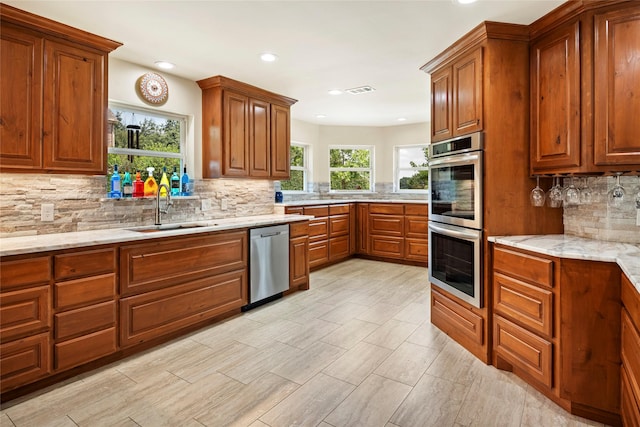 750 Emerald Sound Blvd, Oak Point, TX 75068 - kitchen featuring appliances with stainless steel finishes, decorative backsplash, brown cabinets, recessed lighting, and light stone countertops
