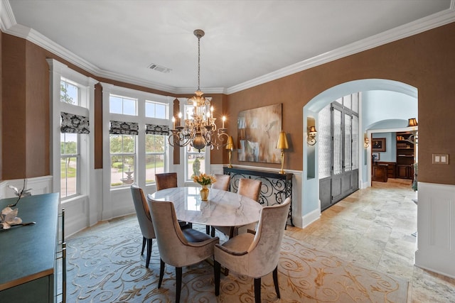 5106 Oak Ln, Arlington, TX 76017 - dining space featuring a chandelier, arched walkways, ornamental molding, wainscoting, and a decorative wall