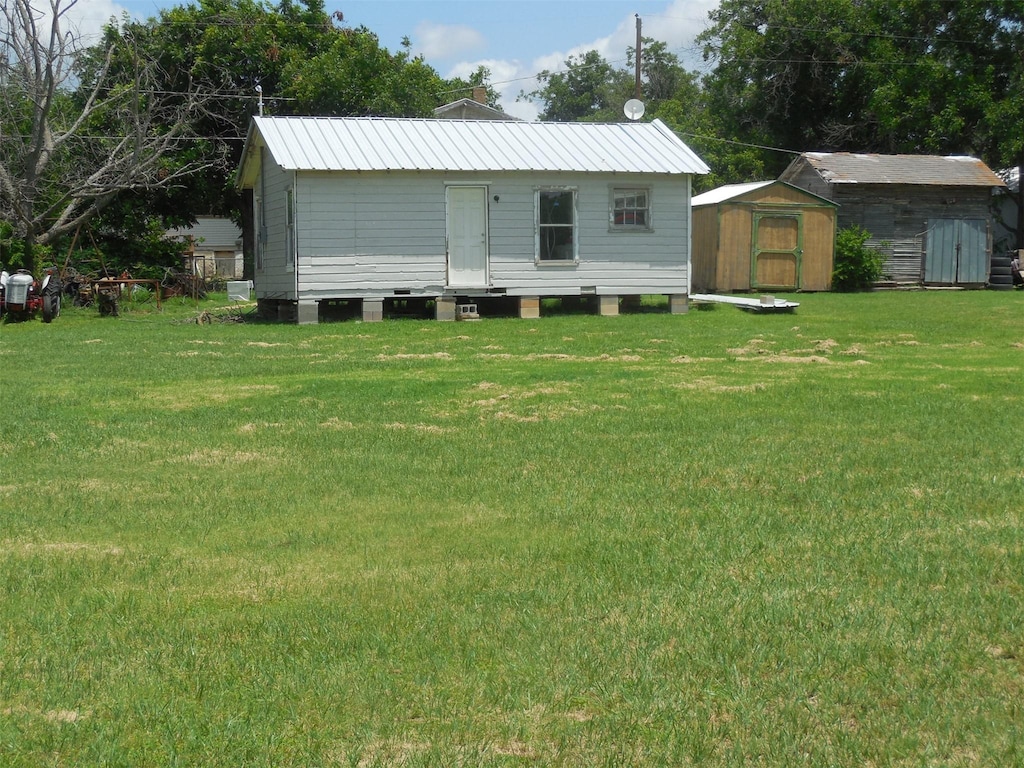 307 Travis St, Ranger, TX 76470 - back of property featuring a shed, a yard, and a metal roof