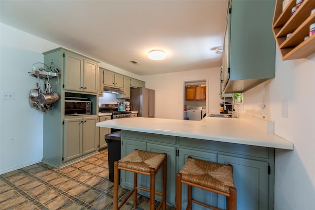 103 Irvin Ln, Mount Vernon, TX 75457 - kitchen with appliances with stainless steel finishes, washer and dryer, a peninsula, under cabinet range hood, and light countertops