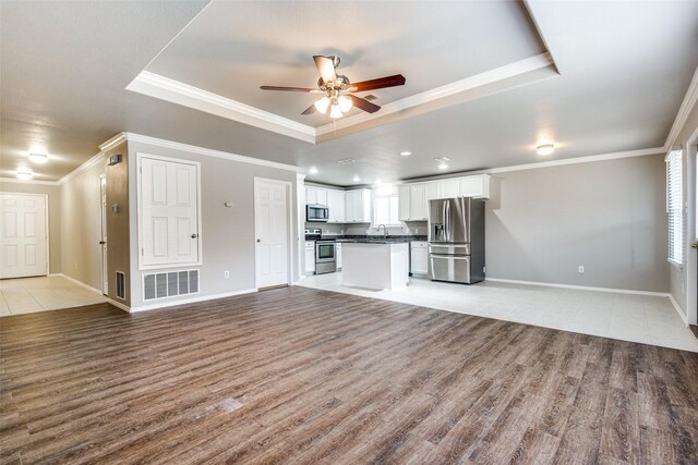 3109 Layla Creek Dr, Little Elm, TX 75068 - unfurnished living room with a tray ceiling, a ceiling fan, light wood-type flooring, and crown molding