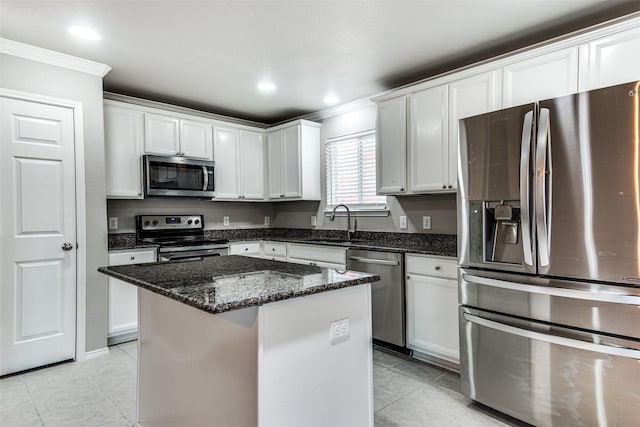 3109 Layla Creek Dr, Little Elm, TX 75068 - kitchen with appliances with stainless steel finishes, ornamental molding, light tile patterned floors, dark stone counters, and a kitchen island