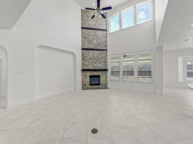 12815 Lourdes Ln, Frisco, TX 75035 - unfurnished living room with a ceiling fan, plenty of natural light, a towering ceiling, arched walkways, and a fireplace