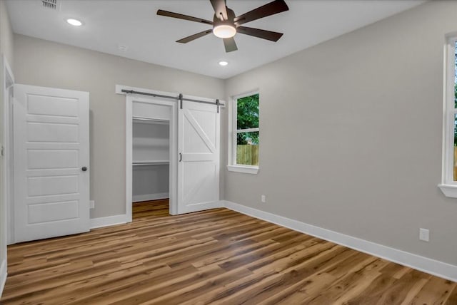 1002 E Main, Whitehouse, TX 75791 - unfurnished bedroom with a barn door, wood finished floors, a ceiling fan, recessed lighting, and a closet