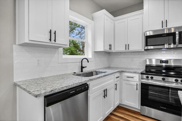 1002 E Main, Whitehouse, TX 75791 - kitchen with appliances with stainless steel finishes, white cabinetry, backsplash, light stone counters, and wood finished floors