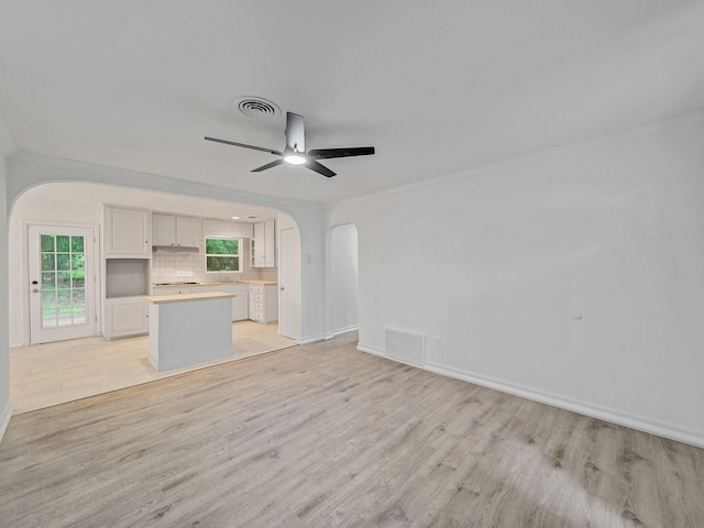 5537 Wheaton Dr, Fort Worth, TX 76133 - unfurnished living room featuring arched walkways, light wood finished floors, ceiling fan, and crown molding