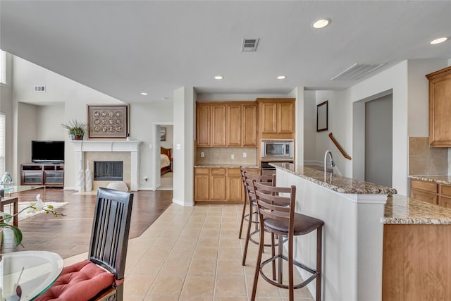 3537 Navarro Way, Frisco, TX 75034 - kitchen with stainless steel appliances, open floor plan, decorative backsplash, a breakfast bar area, and recessed lighting